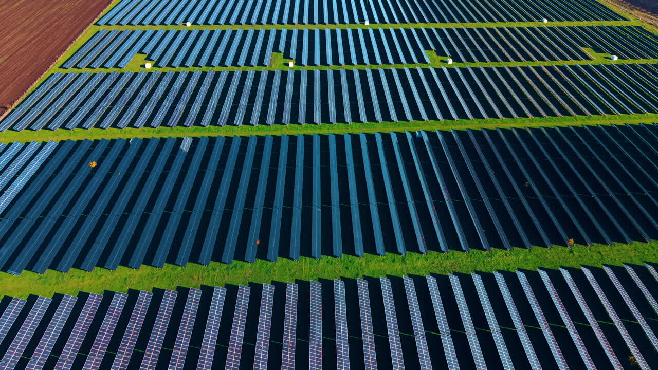 Muovendosi sopra il campo di pannelli solari in campagna. Le celle fotovoltaiche convertono la luce solare in elettricità. Vista aerea.