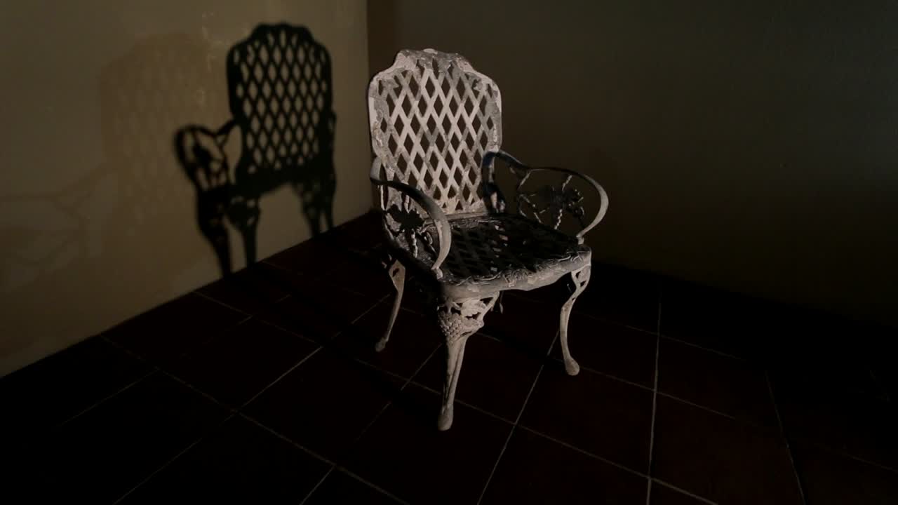 Old wrought iron chair casting shadow against wall