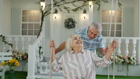 Senior-couple-together-in-front-yard-at-home.-Man-swinging-woman-during-Coronavirus-quarantine