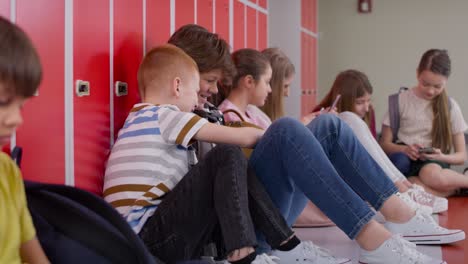 tracking video of schoolchildren using smartphone in corridor near lockers