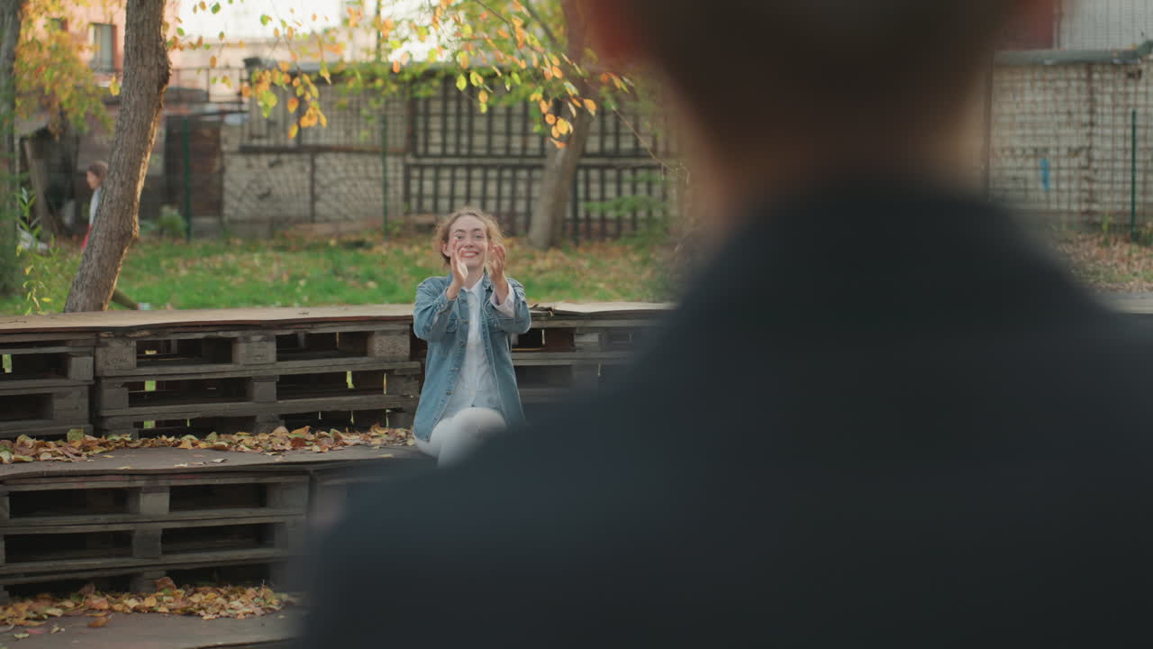 Over shoulder park white woman smiling blurred partner foreground denim jacket wooden pallet seating autumn leaves warm sunlight intimate conversation vowlike exchange emotional family promise