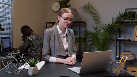 Focused-businesswoman-waving-hand-hi-hello-bye,-talking,-looking-into-laptop-computer-at-home-office