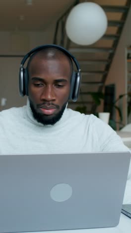 man working on laptop with headphones