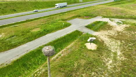 Aerial-view-of-a-highway-with-trucks-and-cars,-and-an-osprey-nest-on-a-pole-by-the-roadside