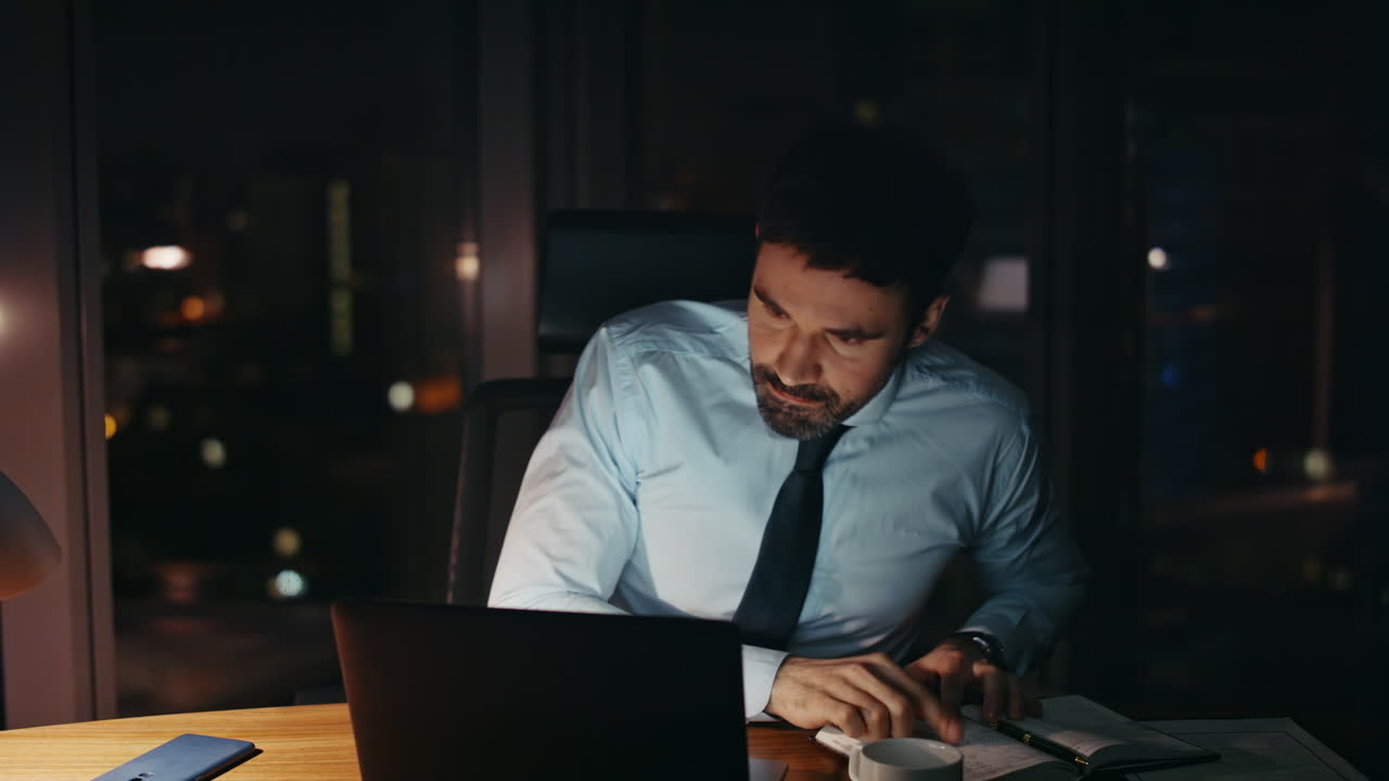 Primo piano di un dipendente aziendale oberato di lavoro che usa il laptop a tarda notte in ufficio da solo.