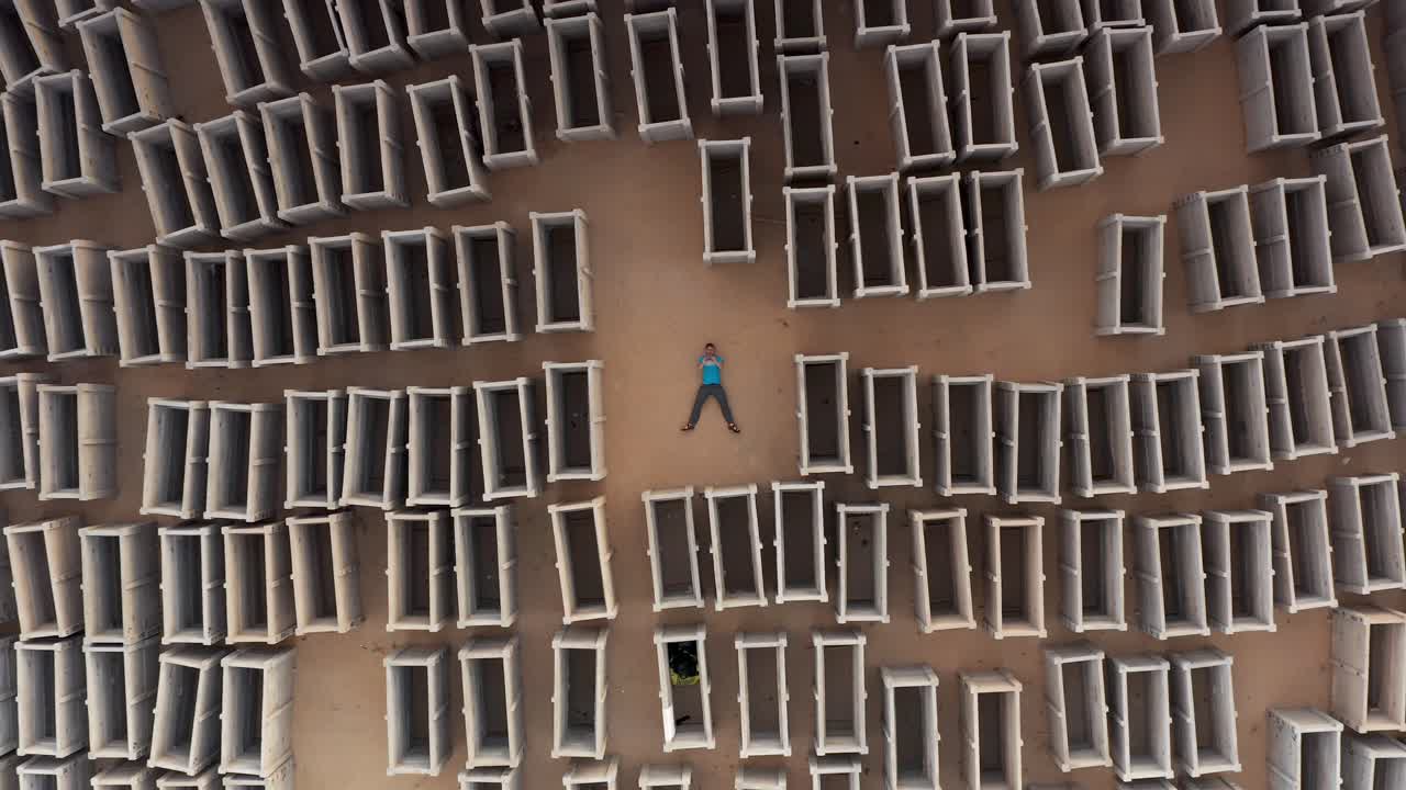 Person Lying in a Field of Cement Grave Boxes