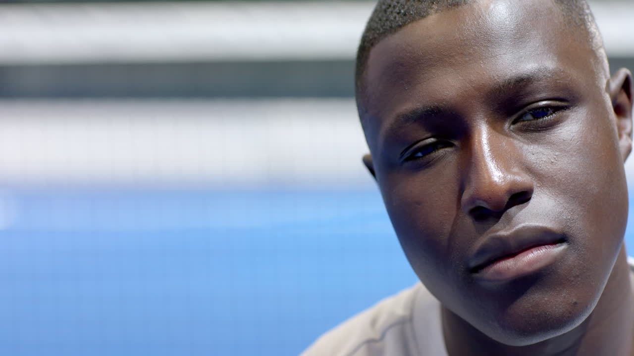 Young man smiling confidently on padel tennis indoor court, enjoying game, copy space