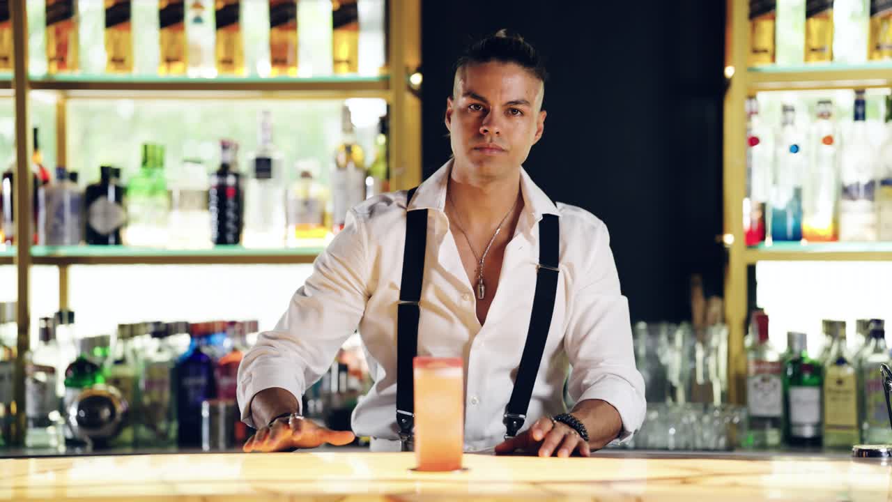 Professionele barman plaatst cocktailglas op bar en kijkt in de camera