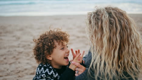 joyful mom kid playing on beach weekend closeup. happy parent spending quality