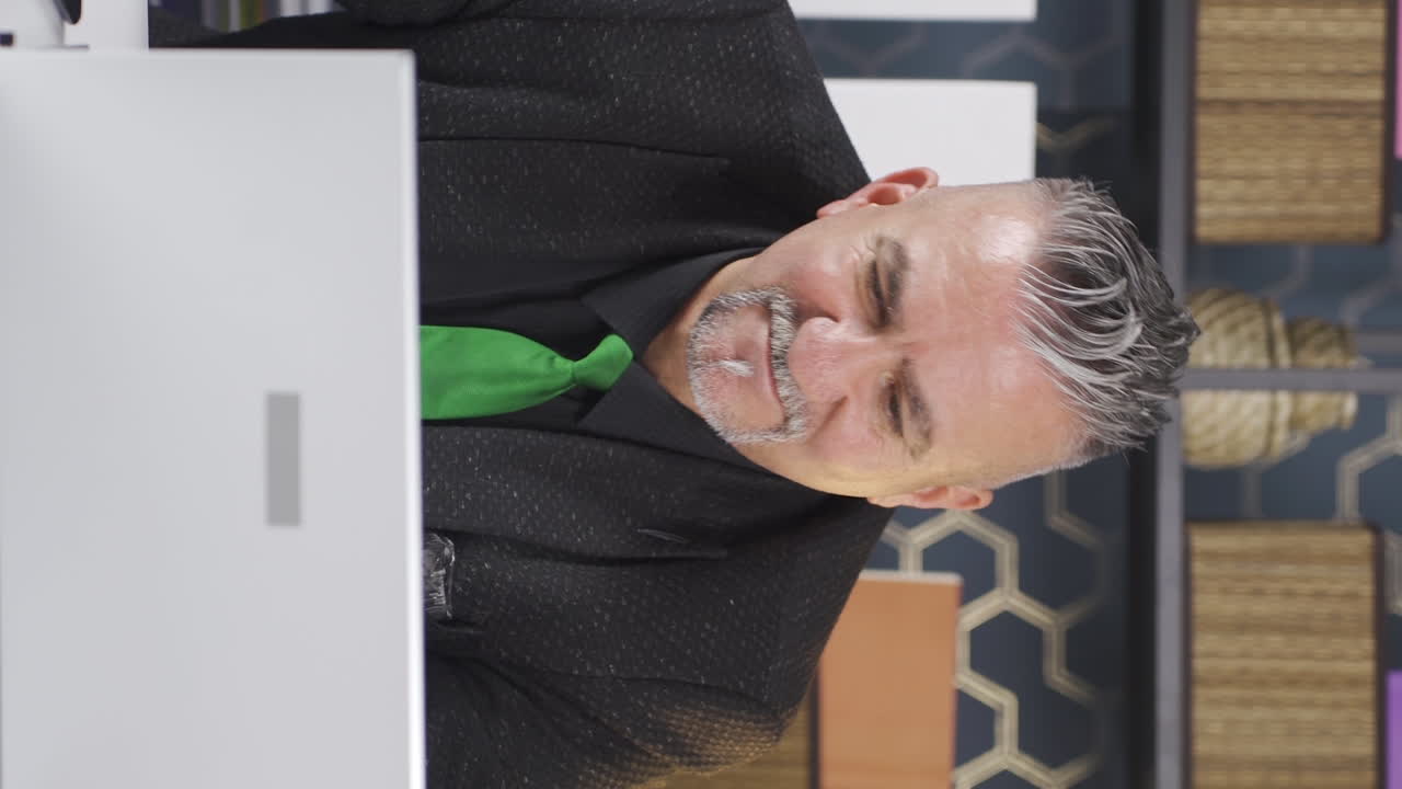 사업가의 수직 비디오는 노트북에서 긍정적인 제스처를 느 ⁇ 니다.