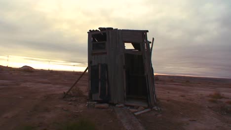 an outhouse stands in the middle of a desert