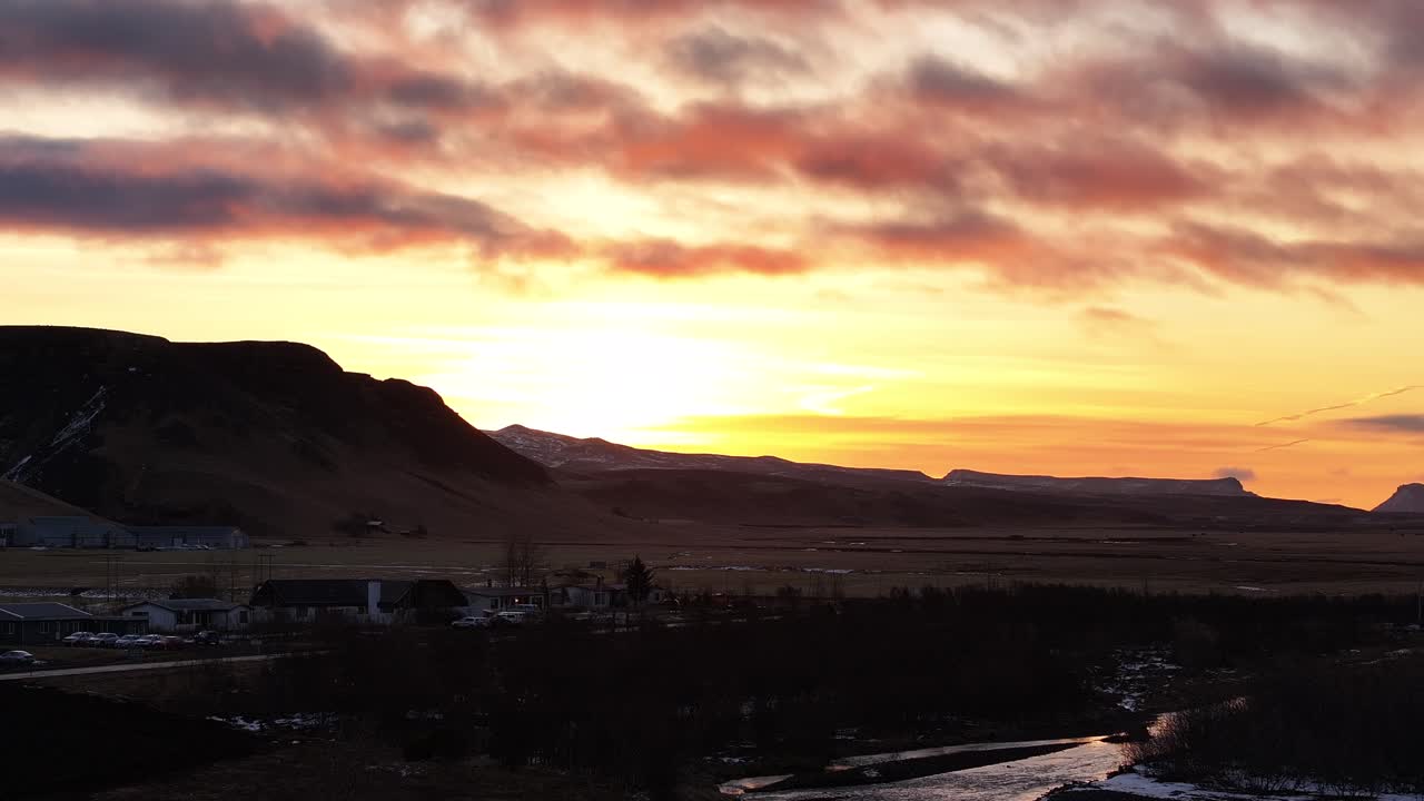Sunset over Iceland valley with glowing clouds and silhouetted mountains