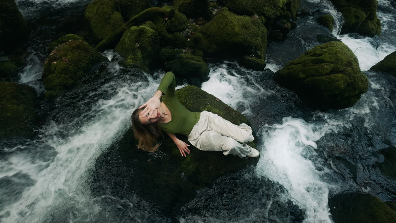 Woman relaxing on rocks by a waterfall