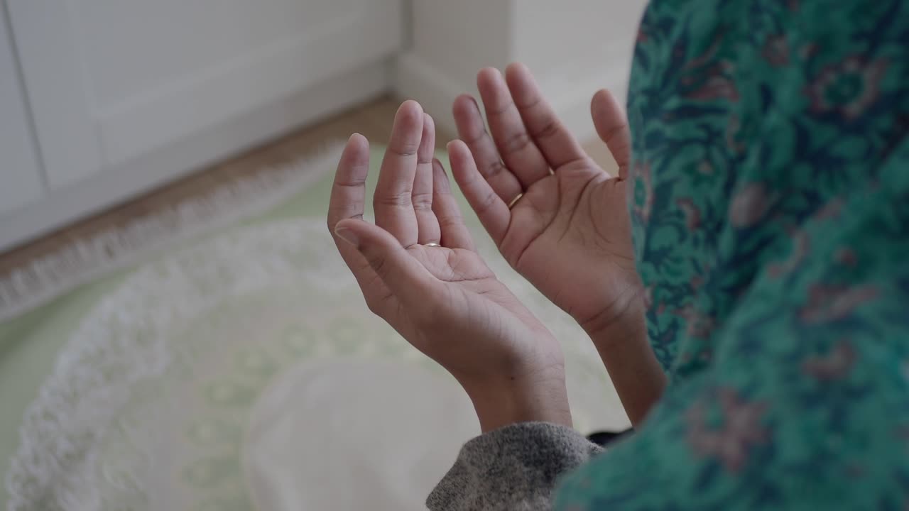 Primo piano di donna musulmana che prega con le mani alzate in supplica