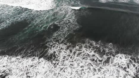 drone flying over crashing waves tilting up and pulling back