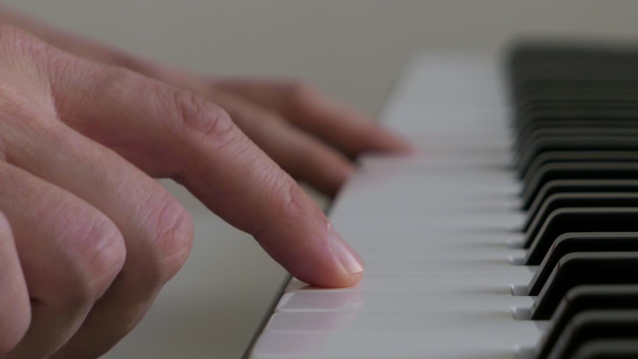Man playing music on piano keyboard, practicing notes, close up