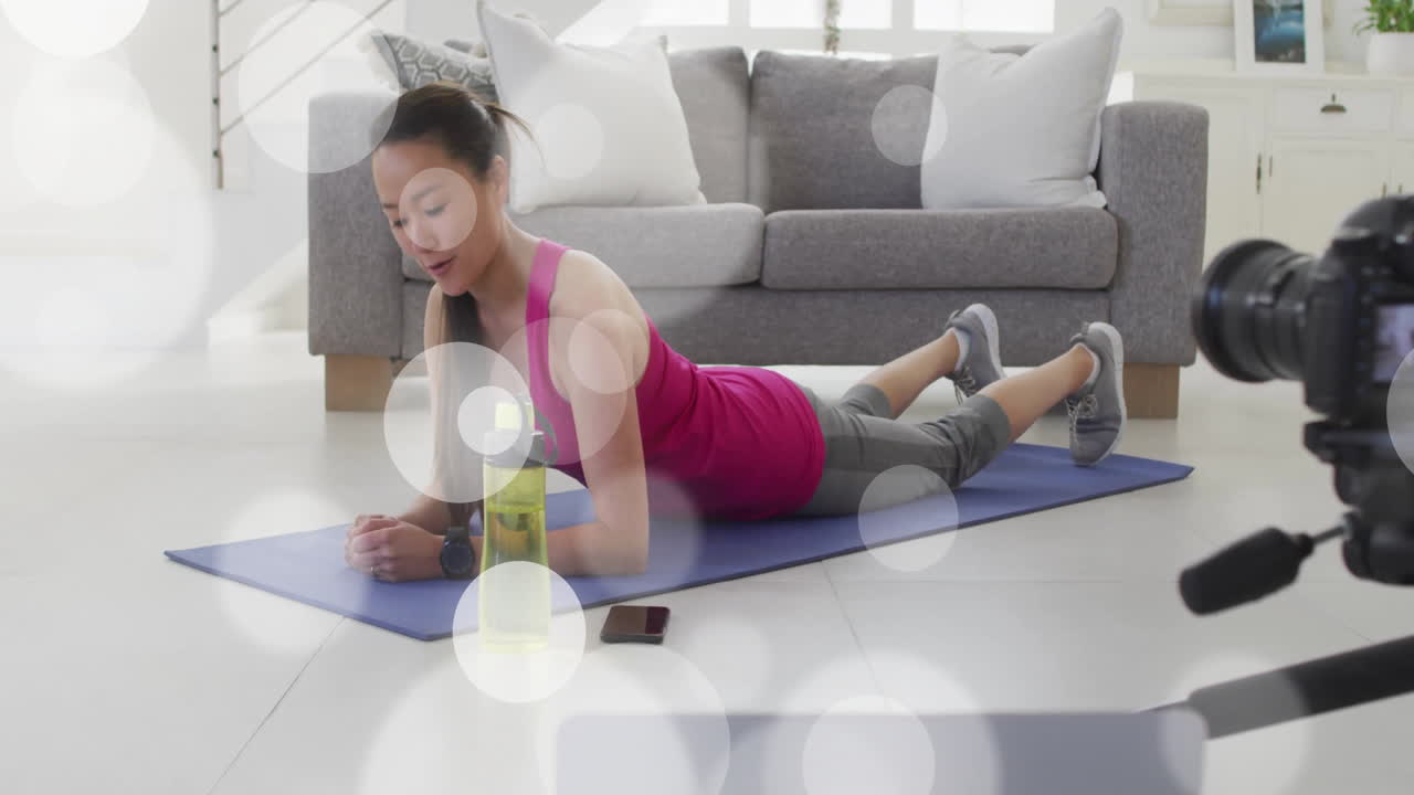 Exercising on yoga mat, woman at home with animation of bokeh light effects