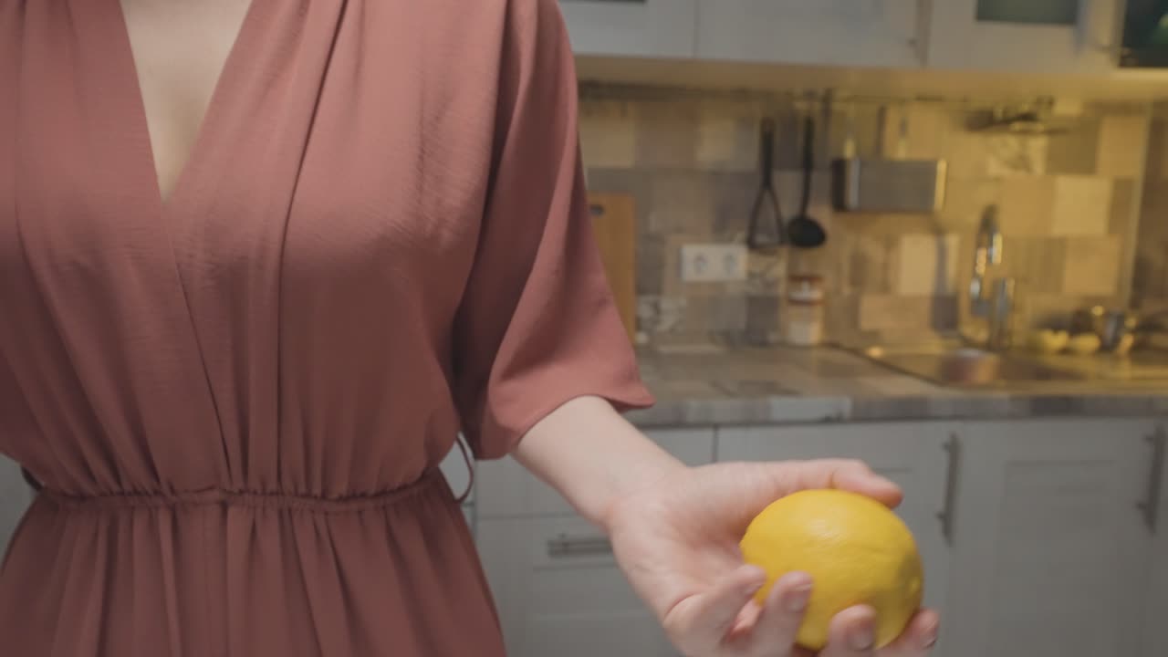 Woman holding a lemon in the kitchen