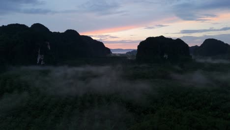 Wunderschöner-Sonnenaufgang-Am-Frühen-Morgen-Mit-Nebel-Und-Kalkstein-Karsttürmen-In-Krabi-über-Der-Landwirtschaftlichen-Palmenplantage