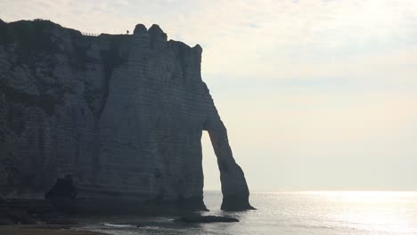 a couple stands on the white limestone cliffs and arches at etretat france english channel