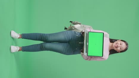 full body of asian woman student showing mock up laptop green screen on green screen studio