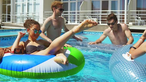 young attractive people swimming on inflatable tubes on the pool party. pretty women and men having a pool party. shot in 4k.