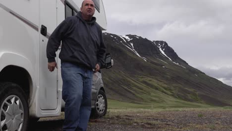 man getting out of rv and looking around at mountain