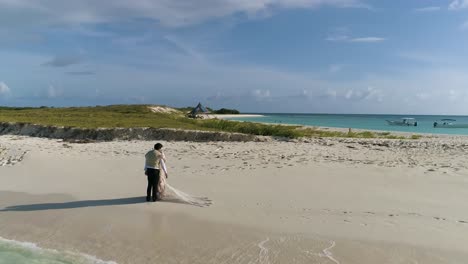 NEWLY-MARRIED-COUPLE-MAN-AND-WOMAN-HUG-ON-WHITE-SAND-SHORE-BEACH,-AERIAL-SHOT-PARADISE-ISLAND