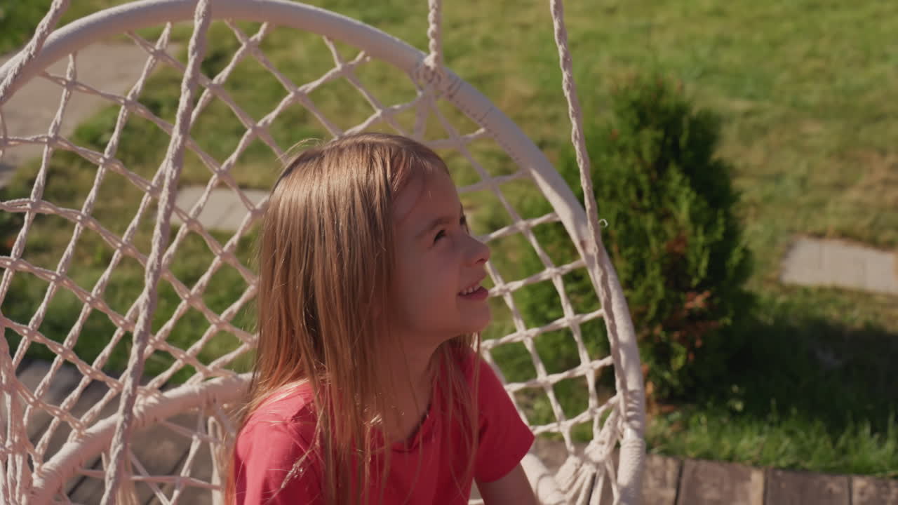 Caucasian Girl Reaching From Swing, Curious Profile Leaning Toward Lawn, Rope And Net Visible, Thoughtful Explorer Expression, Soft Sunlight On Hair, Candid Backyard Study Of Motion And Discovery