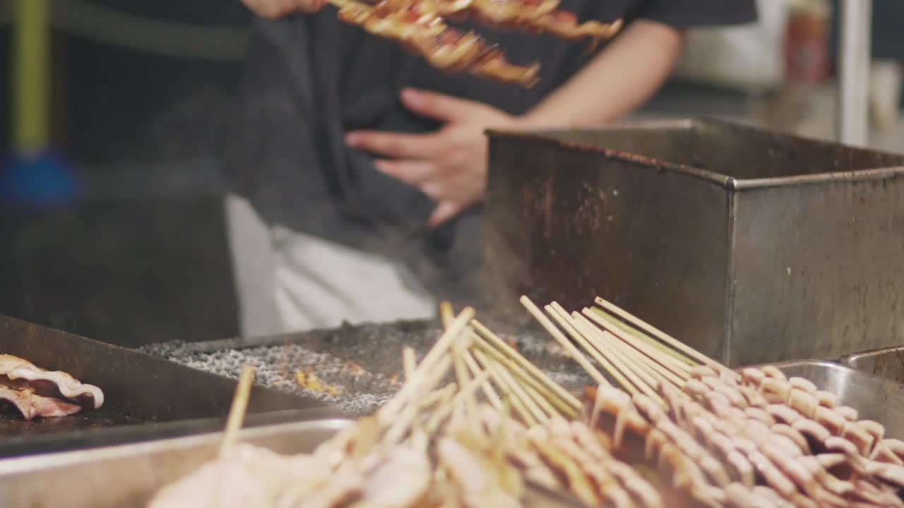 vendedor de comida yatai vendiendo brochetas de calamares a la parrilla durante el festival yoiyama en la noche del festival gion matsuri en kyoto, japón - cerrar cámara lenta