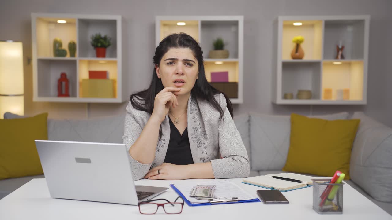 una trabajadora de oficina en casa recibe malas noticias de la cámara.