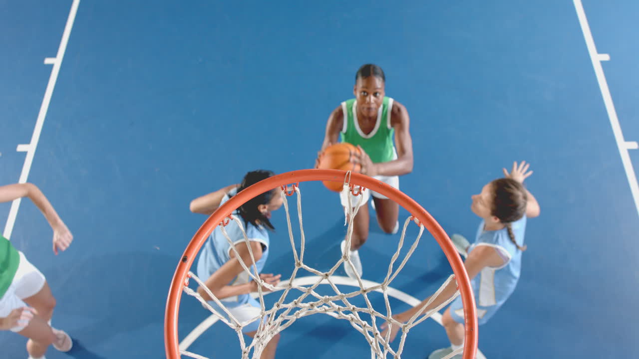 Playing basketball, women jumping to shoot ball into hoop on court