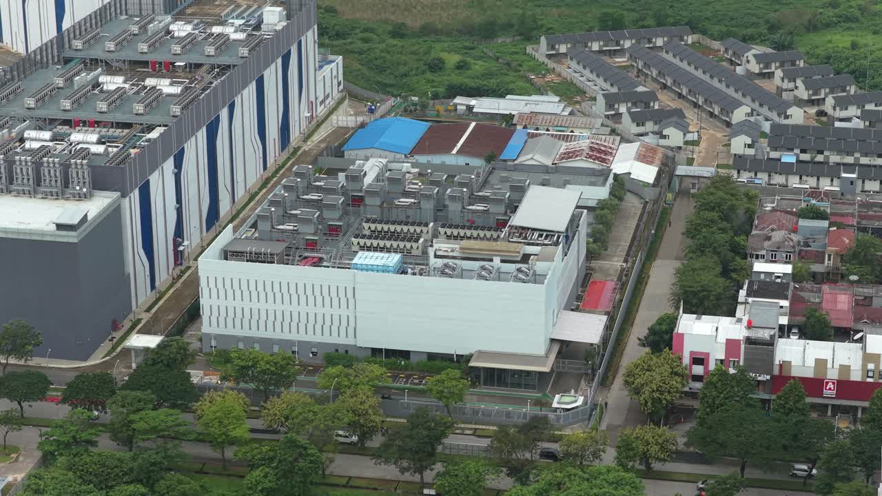 Luftfoto af et moderne datacenterkompleks med kølesystemer på taget, beliggende i et byområde i Jakarta, Indonesien.