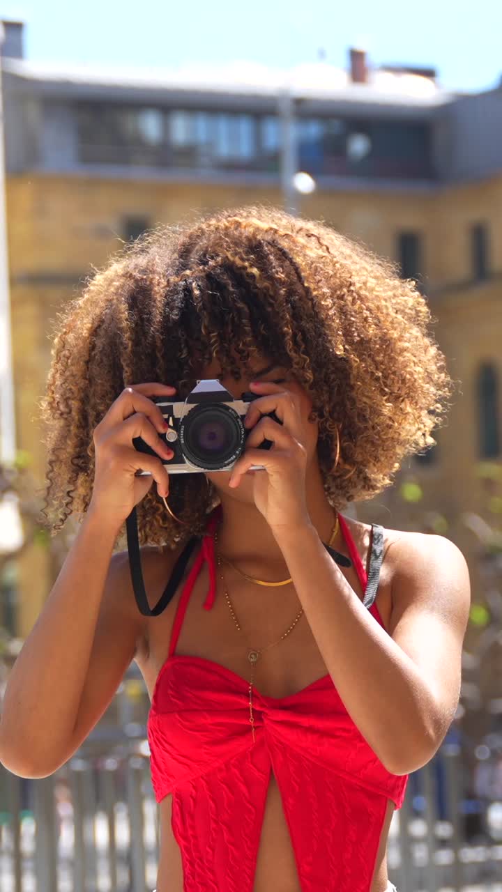 Donna con i capelli ricci che scatta foto in città