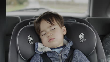 a sleeping boy of two years old rides in a car seat