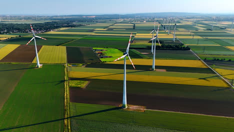 agricultural fields of diverse colors in the countryside. wind mills are rotating in the wind. aerial view.