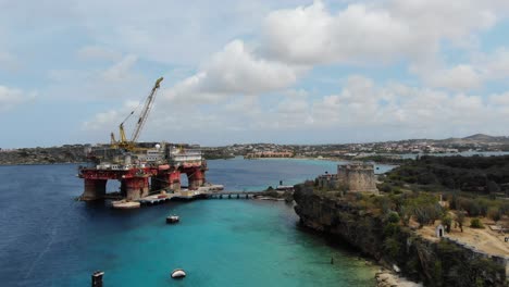 Enormous-industrial-harbor-complex-in-tugboat-beach-with-an-oil-platform-in-curaçao,-aerial-view