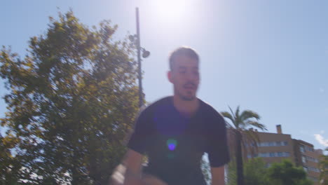 Dynamic-medium-shot-of-a-young-Caucasian-dribbling,-shooting-and-basket-in-a-street-basketball-court-in-Barcelona,-Spain