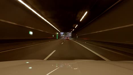 drive through munich, a bavarian capital trip by car at the evening. speeded up from the engine hood view at the late evening with illuminated lanterns and modern buildings.