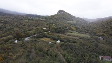 Vista-Aérea-De-La-Carretera-Rural-Del-Pueblo-De-Montañas-En-Hermosos-Prados-Verdes-Valle-De-Las-Montañas