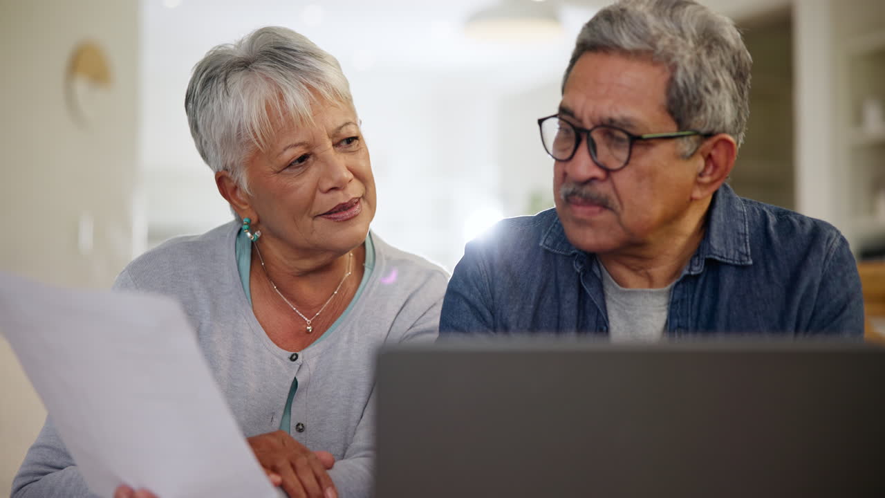 Casal idoso, laptop e documentos.