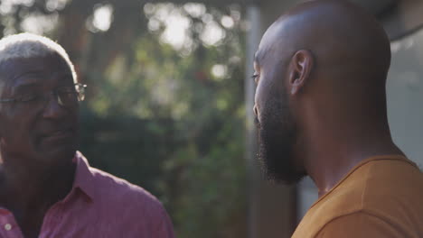 Senior-Father-Talking-And-Laughing-With-Adult-Son-In-Garden-At-Home