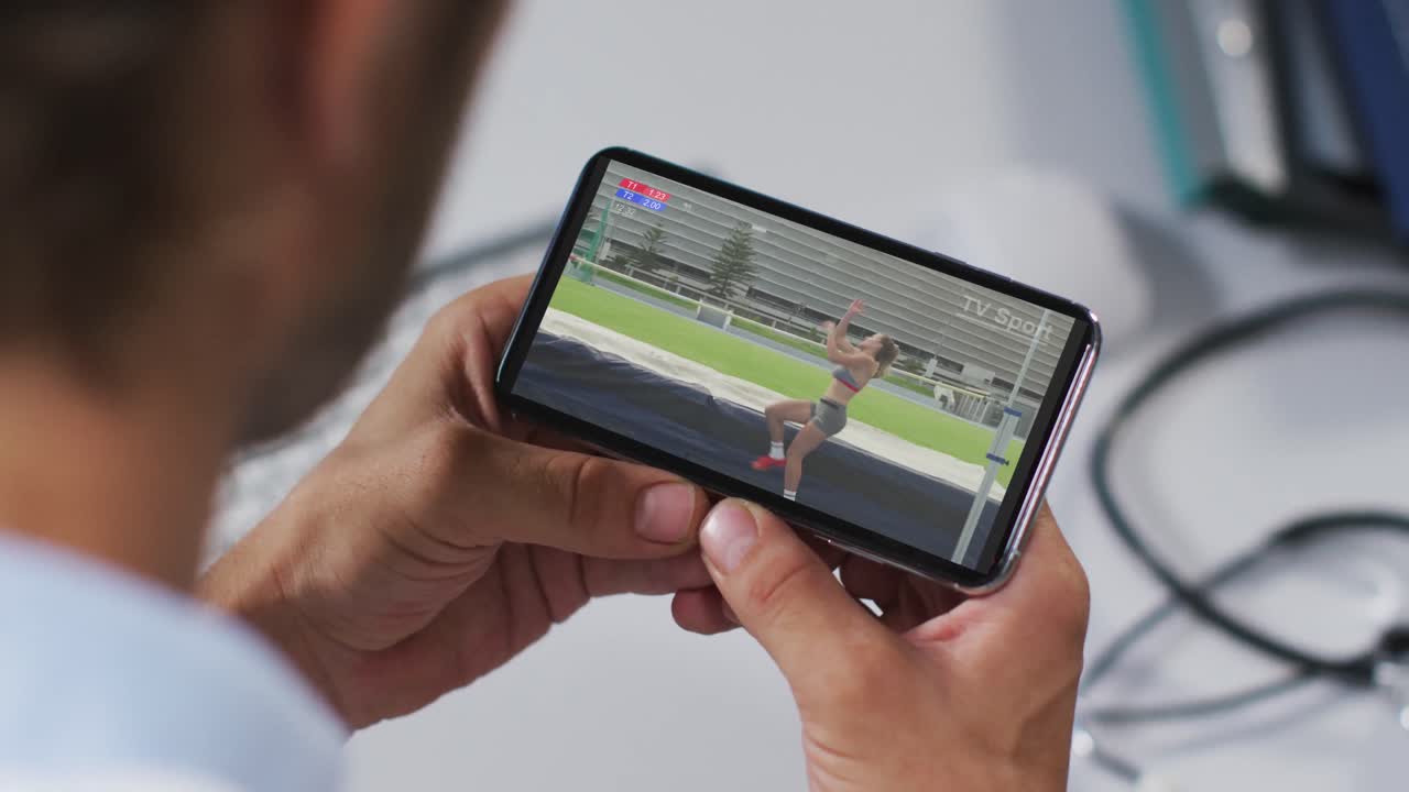 스마트폰으로 육상 높이뛰기 경기를 시청하는 남성 의사의 복합 사진