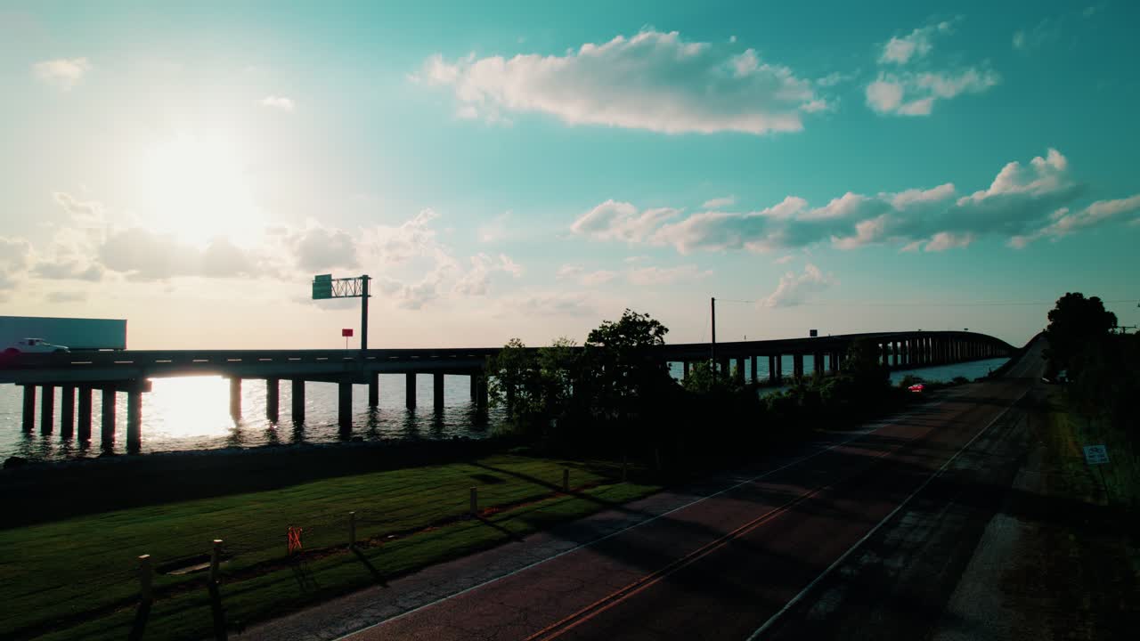 A semi-truck silhouette travels over a sunlit elevated bridge in Louisiana, american freight importance