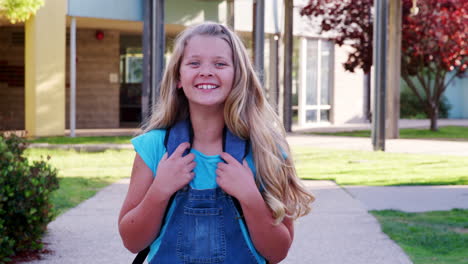 white schoolgirl walking to camera smiling, outside school