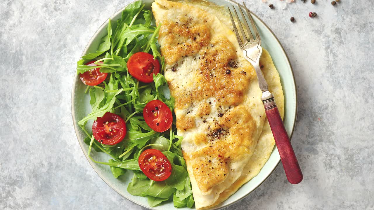 tortilla de huevo clásica servida con tomate cherry y ensalada de rúcula al lado