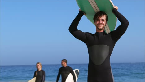 amigos en traje de mojado sosteniendo una tabla de surf