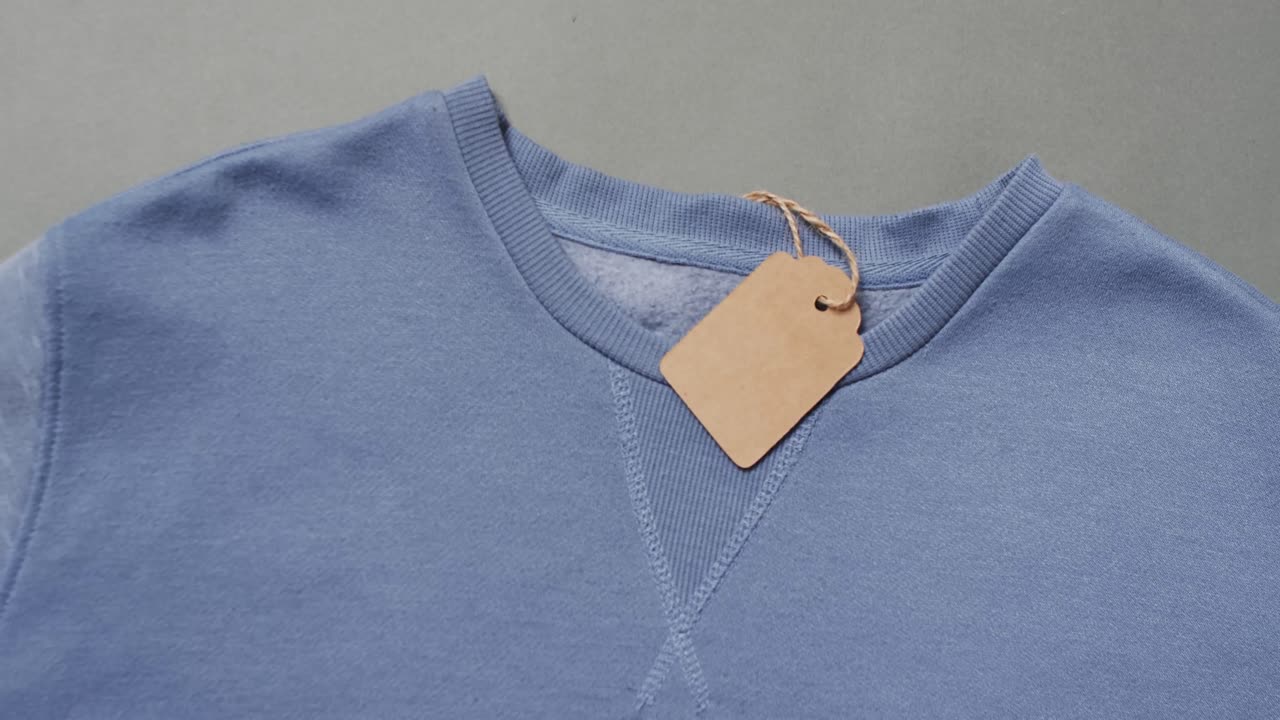 video de una capa plana de camiseta azul con etiqueta y espacio de copia en fondo gris