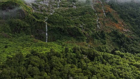 Suaves-Cascadas-Descienden-Sobre-Una-Empinada-Escarpa-De-Frondosos-Bosques-Debajo-De-Las-Nubes