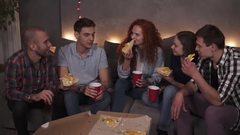 Young-People-Cheerful-Men-And-Women-Are-Eating-Cheesy-Pizza,-Chatting-Relaxing-During-Indoor-Party-In-Apartment-In-A-Loft-Room